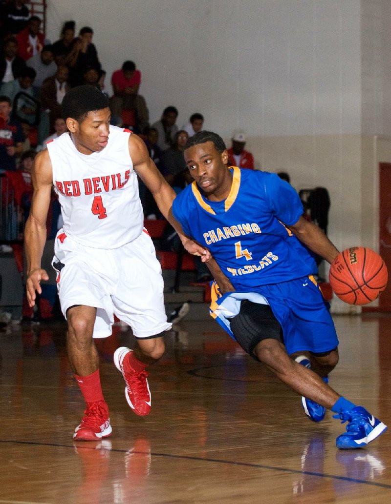 North Little Rock’s Dayshawn Watkins (right) dribbles past Jacksonville’s Justin McCleary (4) during the Charging Wildcats’ 60-52 victory over the Red Devils on Tuesday in Jacksonville. 