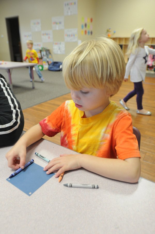 Ryan Fritsche decides how to arrange his crayons to frame his Christmas tree ornament Friday at Just Like Home Childcare-West in Fayetteville. 