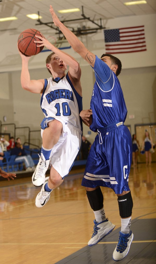 Rogers’ Keifer Holt, left, takes the ball to the basket under pressure from Conway’s Dominic Taylor during the Mounties’ game Tuesday against the Wampus Cats at King Arena in Rogers. 