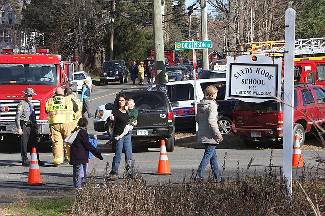 Parents walk away from the Sandy Hook Elementary School with their children following a shooting, Friday, Dec. 14, 2012 in Newtown, Conn.