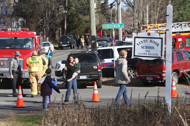 Parents walk away from the Sandy Hook Elementary School with their children following a shooting, Friday, Dec. 14, 2012 in Newtown, Conn.
