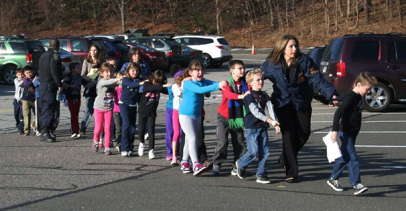 A Connecticut State Police trooper leads children out of Sandy Hook Elementary School in Newtown, Conn., on Friday. The youngsters were told to close their eyes as they left. 