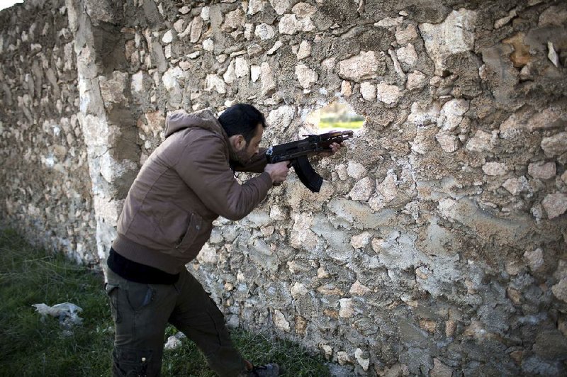 A Syrian rebel ÿres through a wall Friday during a battle with government forces in Tal Sheer. 