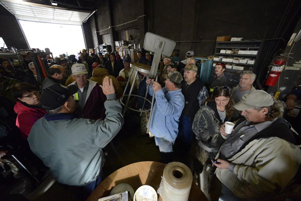 Darrell Seaman, center, holds up a metal chair Friday as auctioneer Mike Price of Price Auction Marketing takes bids during an inventory liquidation sale at Lincoln Supply Company in Lincoln. 