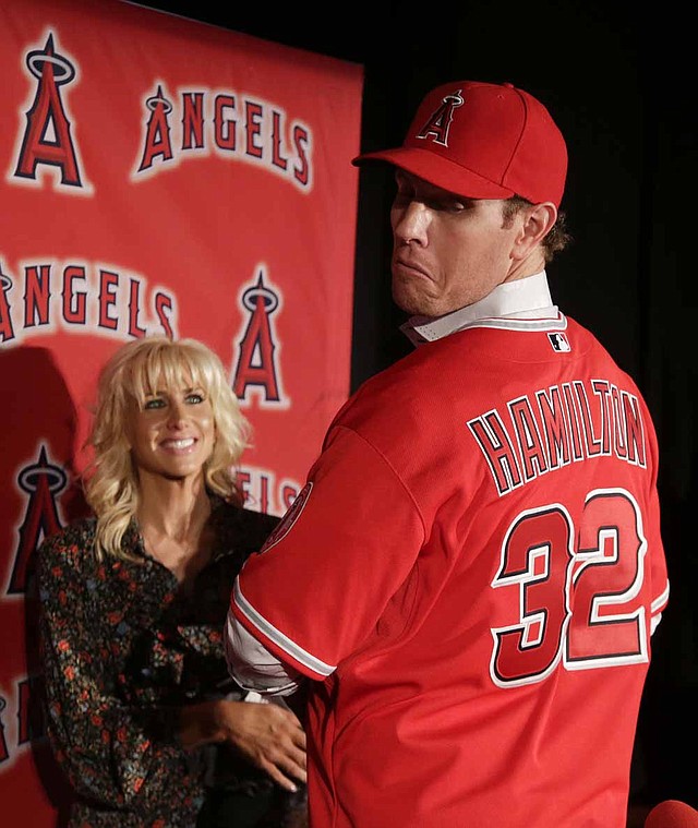 Free-agent outfielder Josh Hamilton models his new Los Angeles Angels jersey for the crowd as his wife, Katie, looks on during an introductory news conference Saturday in Anaheim, Calif. 