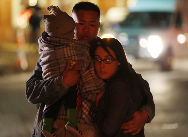 Johnny Nhatavong, center, of New Haven, Conn., embraces his wife, Melennie Rizek, right, and their 11-month-old son Kenzo Jung while stopping at a makeshift memorial near the place where a day earlier a gunman opened fire inside of an elementary school, Saturday, Dec. 15, 2012, in Newtown, Conn. The man, who died from a self-inflicted wound, allegedly killed his mother at their home and then opened fire Friday inside the Sandy Hook Elementary school, massacring 26 people, including 20 children.