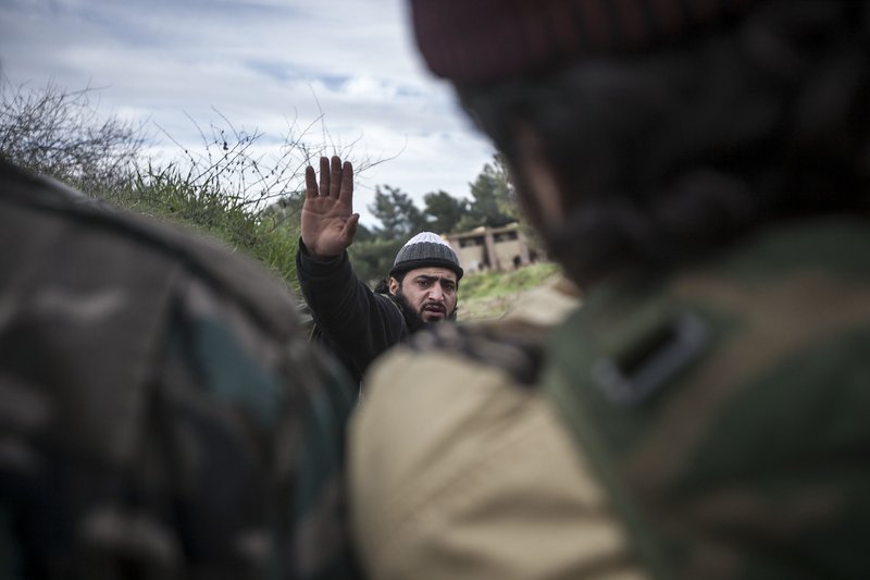 In this Saturday, Dec. 15, 2012 photo, a Free Syrian Army fighter leads his comrades during heavy clashes with government forces at a military academy besieged by the rebels north of Aleppo, Syria. Free Syrian Army fighters took control over the military academy after battling government forces for several hours.