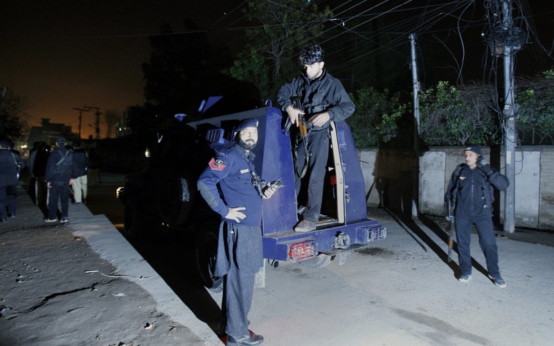 Pakistani police officers gather beside an armored vehicle near the site of rocket attack by militants in Peshawar, Pakistan on Saturday, Dec. 15, 2012. Militants fired three rockets at an airport in the northwestern Pakistani city of Peshawar on Saturday night, killing several people and wounding dozens, officials said. 