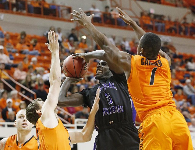 Central Arkansas guard Robert Crawford (0) goes up for a shot between Oklahoma State’s Christien Sager (left) and Kirby Gardner during the second half of Sunday’s game in Stillwater, Okla. The Bears led early, but No. 24 Oklahoma State won 91-63. 