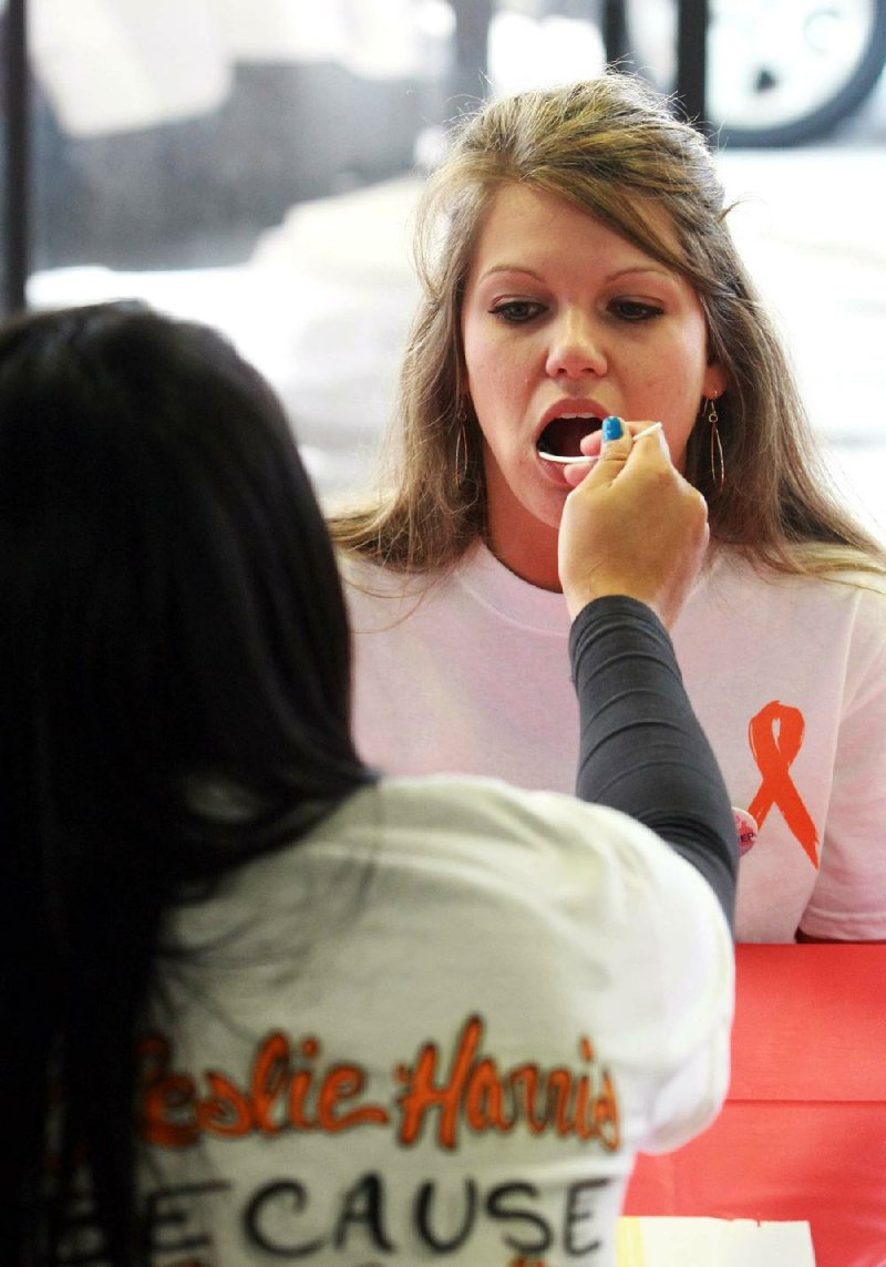 Nittara Lauland swabs the mouth of Amber Church during a March bone-marrow drive at the Lakewood Village Shopping Park in North Little Rock. 