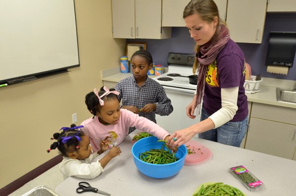 Ally Mrachek, a FoodCorps Service Member, right, works with Vyleria Hull, from left, 3, Syveria Hull, 5, and Kenderick Hull, 8, as they prepare a meal during a family cooking class at Holt Middle School in Fayetteville. FoodCorps volunteers in the Fayetteville School District were conducting the family food class to show families ways to cook healthy meals. 
