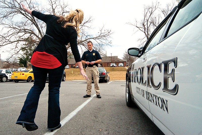 Lt. Kevin Russell, right, of the Benton Police Department looks on as department employee Valarie Boyette demonstrates part of the roadside sobriety test.