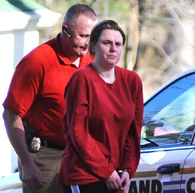 Arkansas State Police investigator Dennis Morris escorts a handcuffed Andrea Davis to a car on Feb. 29 after the body of Maxwell Anderson was found outside her home. No one has been charged in the case, which officials said Tuesday remains “active.” 