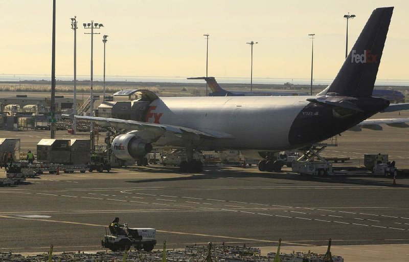 FILE - In this Tuesday, Dec. 11, 2012 file photo, FedEx workers unload packages from a cargo plane at the Oakland Regional Sort Facility in Oakland, Calif. FedEx is more pessimistic about the U.S. economy than it was three months ago, but more assured of its own ability to grow earnings. The world's second-largest package delivery company lowered its economic forecast for the U.S., saying that there remains a lot of uncertainty for the company and the country. Its forecast for the current quarter, which incorporates the critical holiday season, falls short of Wall Street expectations. (AP Photo/Ben Margot, File)