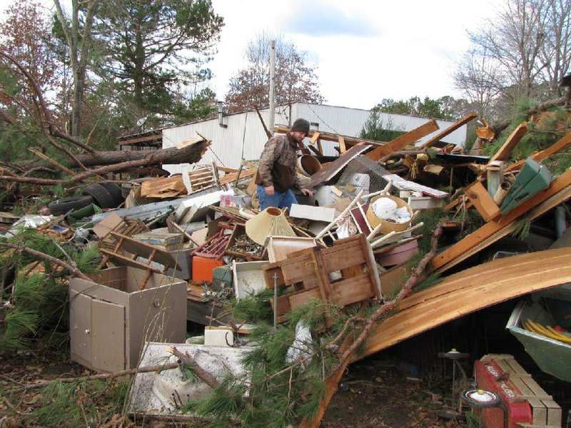 Joey Chadick, 25, works Thursday to salvage Christmas presents that were kept in a storage shed that was smashed in an overnight storm. Chadick’s Grant County home was slightly damaged, as well. More photos are available at arkansasonline.com/galleries. 