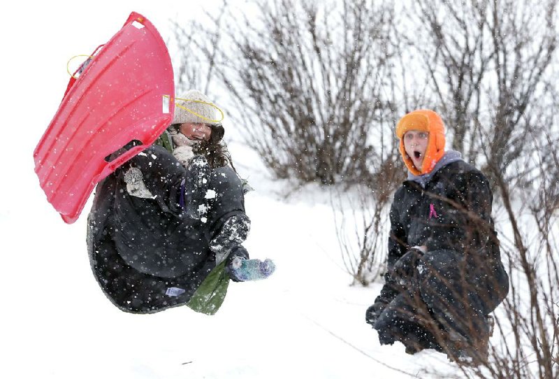 Nathan Disch watches in astonishment as Carina Panella catches some air while sledding Thursday at a park during a winter storm in Grand Chute, Wis. 