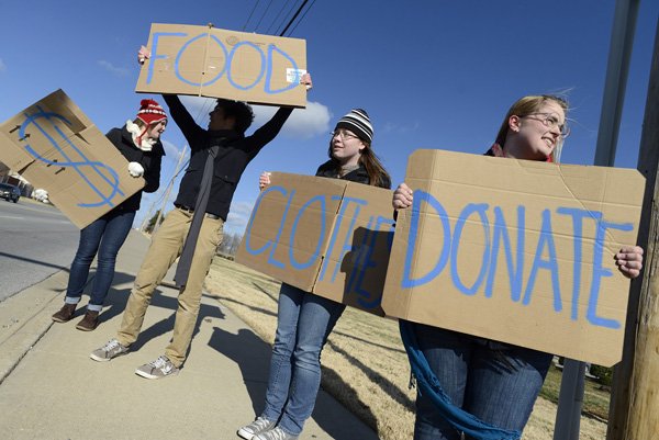Samantha Farley, from left, 16, Keaton Duersch, 16, Katie Wilson, 17, and Emma Hackett, 17, wave signs at motorists Thursday along Southeast J Street in Bentonville to advertise their donation station in front of Bentonville High School. The students, members of Amnesty International’s Bentonville High School chapter, were taking food donations for the Northwest Arkansas Food Bank and clothing and monetary donations for the Northwest Arkansas Women’s Shelter. The event continues from 6 to 11 a.m. today.
DONATION STATION 