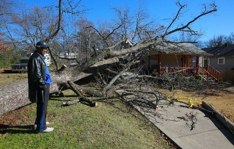 David Jackson walks around his damaged home at 20th and Martin streets Friday in Little Rock. A tree fell on the house during Thursday’s storm. More photos are available at arkansasonline.com/galleries. 
