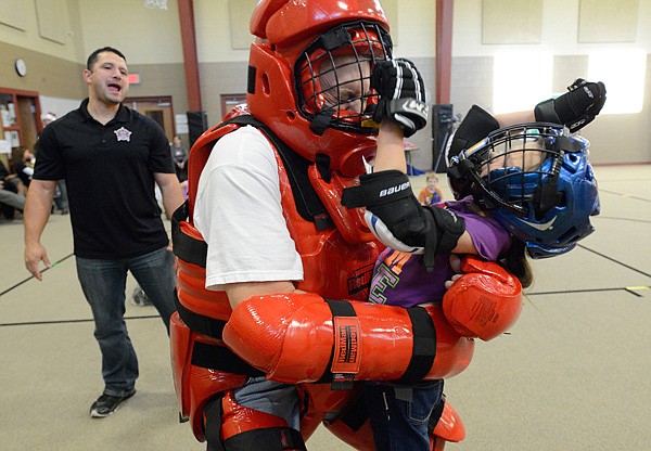 Jessi Baldwin, 9, right, strikes Doug Gay, Benton County Sheriff’s Office deputy, as Cpl. Scott Santos gives instruction Thursday during a breakaway self-defense scenario for the children participating in the radKIDS program at Cooper Elementary School in Bella Vista. 