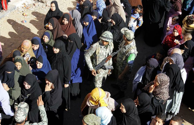 Egyptian soldiers stand between lines of voters in Giza on Saturday during the second round of a referendum on a new constitution. 