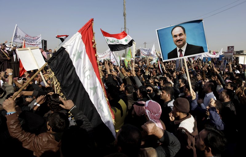 Protesters chant slogans against the Iraq's Shiite-led government as they wave national flags and hold posters of the Sunni Finance Minister Rafia al-Issawi during a demonstration in Fallujah, 40 miles west of Baghdad, Iraq, Sunday, Dec. 12, 2012. Thousands of protesters have demonstrated in Iraq's western Sunni heartland following the arrest of bodyguards assigned to the finance minister, who draws support from the area.