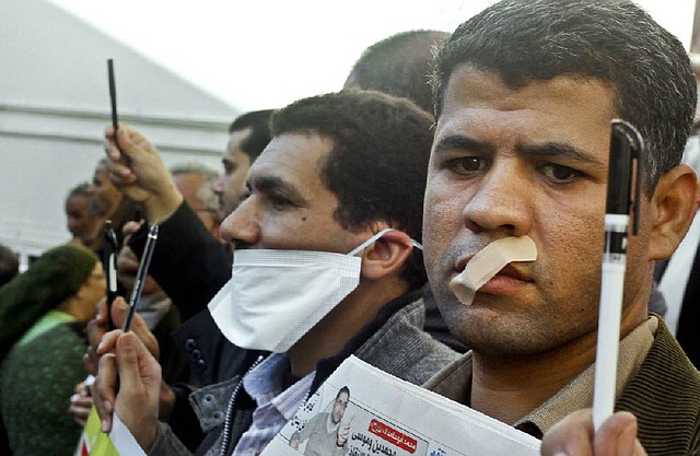Egyptian journalists tape their mouths and raise their pens during a demonstration against the draft constitution in Cairo, Egypt, Sunday, Dec. 23, 2012. Egypt's opposition called Sunday for an investigation into allegations of vote fraud in the referendum on a deeply divisive Islamist-backed constitution after the Muslim Brotherhood, the main group backing the charter, claimed it passed with a 64 percent "yes" vote. Official results have not been released yet and are expected on Monday. (AP Photo/Amr Nabil)