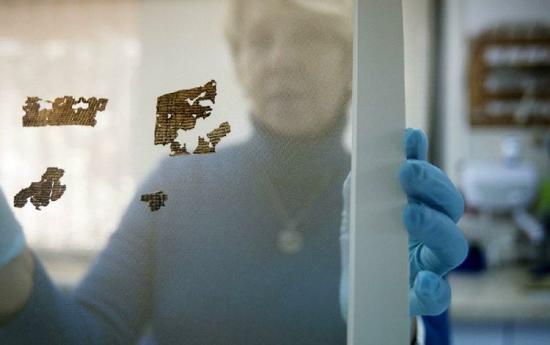 A worker of the Dead Sea Scrolls conservation laboratory at the IAA, Israel Antiquities Authority, holds a frame with small fragments of the Dead Sea Scrolls in a laboratory in Jerusalem, Tuesday, Dec. 18, 2012. Israeli authorities say they have put 5,000 fragments of the ancient Dead Sea scrolls online in a partnership with Google.(AP Photo/Dan Balilty)