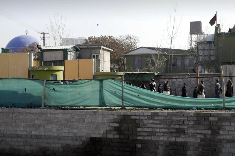 Afghans walk past by a gate of the Kabul police headquarters, where an American advisor was killed in Kabul, Afghanistan, Monday, Dec. 24, 2012. An Afghan policewoman killed an American adviser at the Kabul police headquarters on Monday, a senior Afghan police official said.