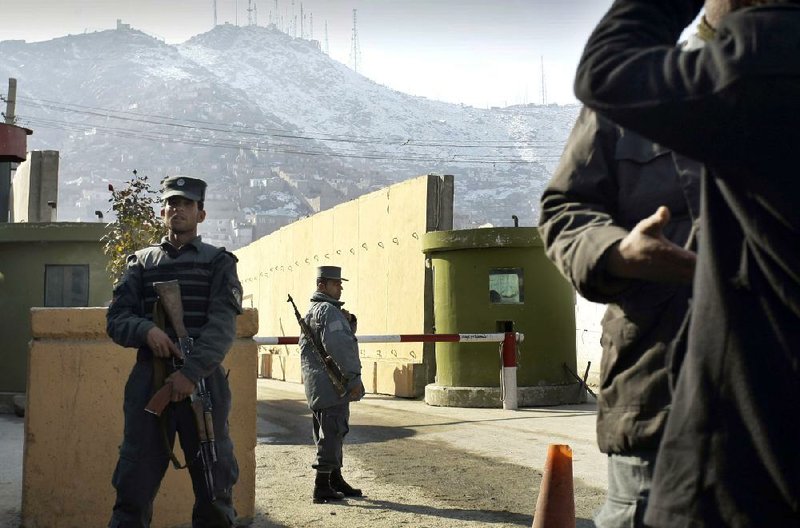 Afghan policemen stand guard outside of Kabul police headquarters, where a an American advisor was killed,  in Kabul, Afghanistan, Monday, Dec. 24, 2014. An Afghan policewoman killed an American adviser at the Kabul police headquarters on Monday, a senior Afghan police official said. (AP Photo/Musadeq Sadeq)