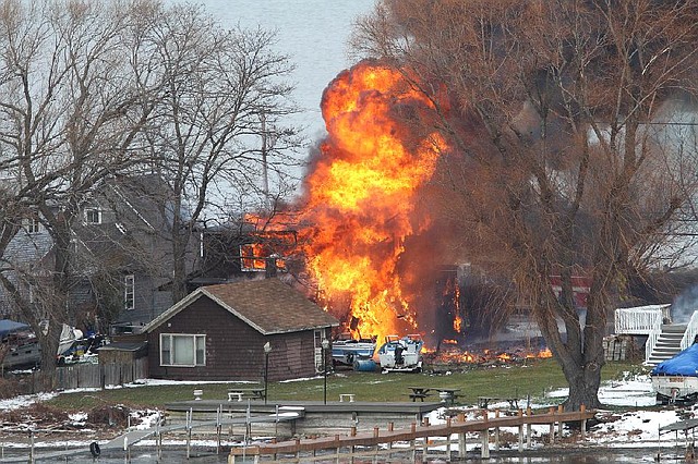 A house burns Monday, Dec. 24, 2012 in Webster, New York. A former convict set a house and car ablaze in his lakeside New York state neighborhood to lure firefighters then opened fire on them, killing two and engaging police in a shootout before killing himself while several homes burned. Authorities used an armored vehicle to evacuate the area. (AP Photo/Democrat & Chronicle, Jamie Germano)