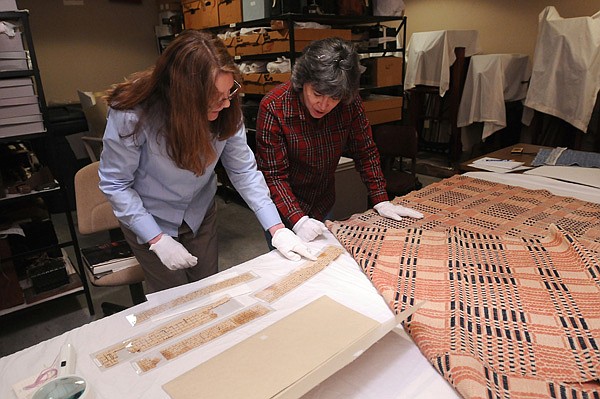 Carolyn Reno (left), collections manager with Shiloh Museum of Ozark History, and Marty Benson, a member of the Northwest Arkansas Handweavers Guild, look over coverlet drafts Dec. 18 at the Springdale museum. Benson and fellow guild member Laura Redford are researching 26 coverlets at the museum to learn more about the way they were made and the lives of the people who made them. 