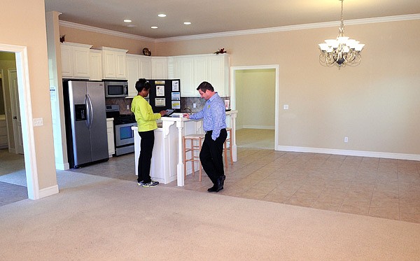 David Wilson, a Realtor with Weichert Realtors, waits as Connie Burklow inputs her information on an iPad after visiting an open house Dec. 16 at 1931 Batsford Drive in Fayetteville. Wilson said the market has improved since the 2008 recession, and he now sees homes selling, depending on the price range, in 60 to 90 days. 