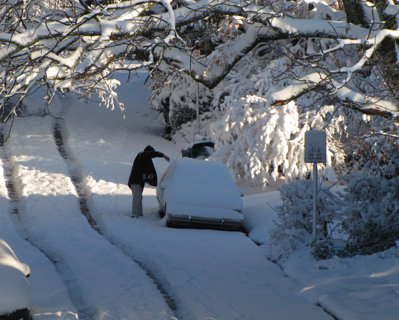 A man attempts to clear his car of snow on Dec. 26, 2012, in Little Rock's Hillcrest neighborhood.