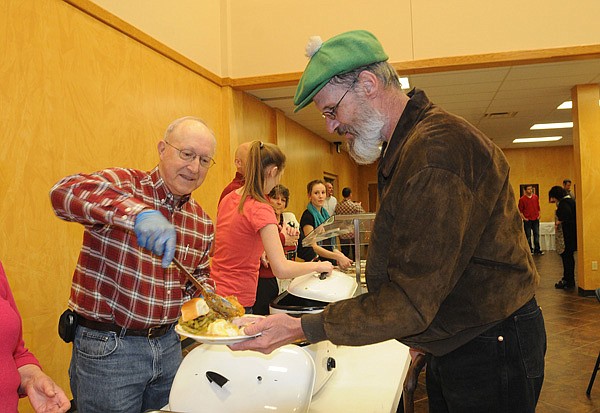 Ed Grames, left, serves a traditional Christmas dinner to John J.C. Colbert on Tuesday at Central United Methodist in Rogers. 