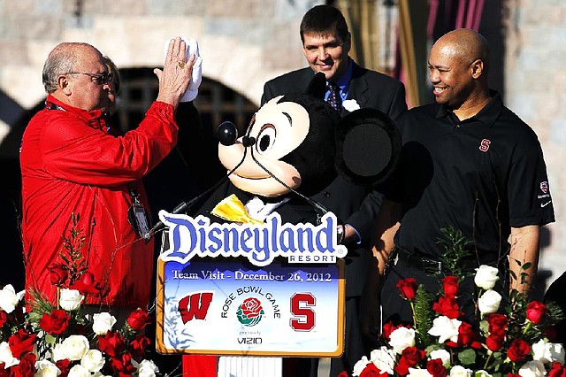 Wisconsin athletic director Barry Alvarez, left, and a person dressed as Mickey Mouse, center, high-five as Stanford head coach David Shaw, right, watches during a news conference at Disneyland in Anaheim, Calif., Wednesday, Dec. 26, 2012. Wisconsin is scheduled to play Stanford in the Rose Bowl NCAA college football game in Pasadena, Calif., on Jan. 1, 2013. (AP Photo/Jae C. Hong)