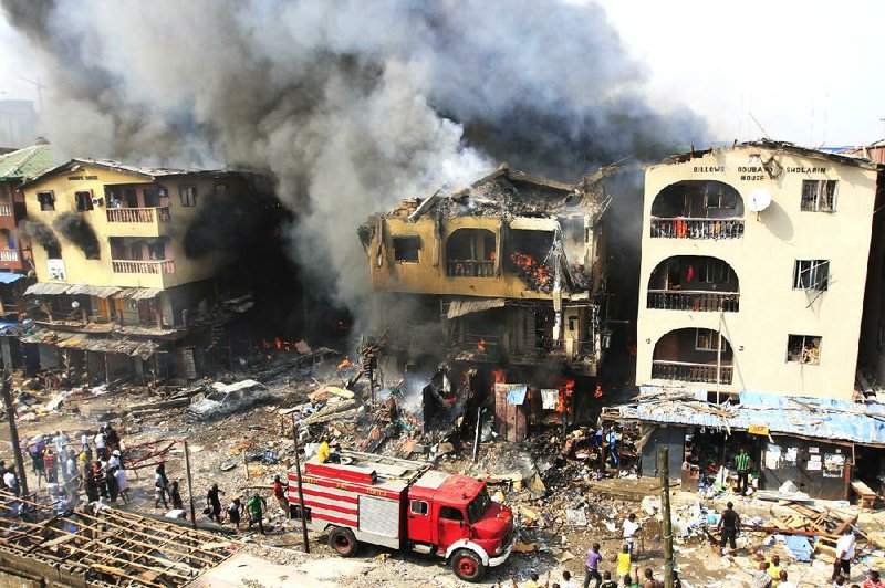 A fire truck passes a warehouse on fire on Lagos Island in Lagos, Nigeria, on Wednesday, Dec. 26, 2012. An explosion ripped through a warehouse Wednesday where witnesses say fireworks were  stored in Nigeria's largest city, sparking a fire. It wasn't immediately clear if anyone was injured in the blast that firefighters and locals struggled to contain. (AP Photo/Jon Gambrell)