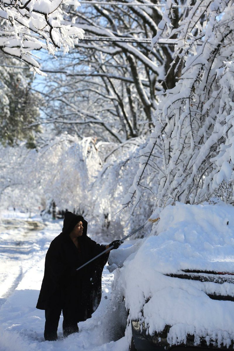 Pamela Richardson uses a broom to clean the snow off her car on West B. Street in North Little Rock Wednesday after several inches of sleet and snow fell Tuesday.