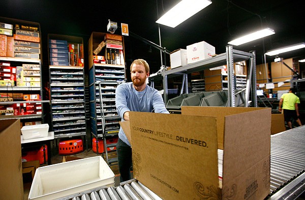Adam Miller sends a CountryOutfitter.com shipment Dec. 7 down the rollers in the warehouse of Acumen Brands. The company is one of several that flourished in Northwest Arkansas during tough economic times. 