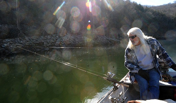 Roy Clark, a trout and walleye guide on the White River below Beaver Dam, checks his line while trolling for trout Dec. 13. Clark trolls spoons or floating Rapala lures for trout during winter. 