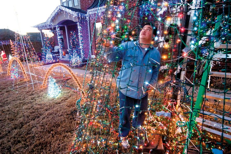 Tony Brighter works on restoring power to lights in a display that is part of his computer-controlled, musical Christmas light show. The display was damaged during high winds earlier in the week.