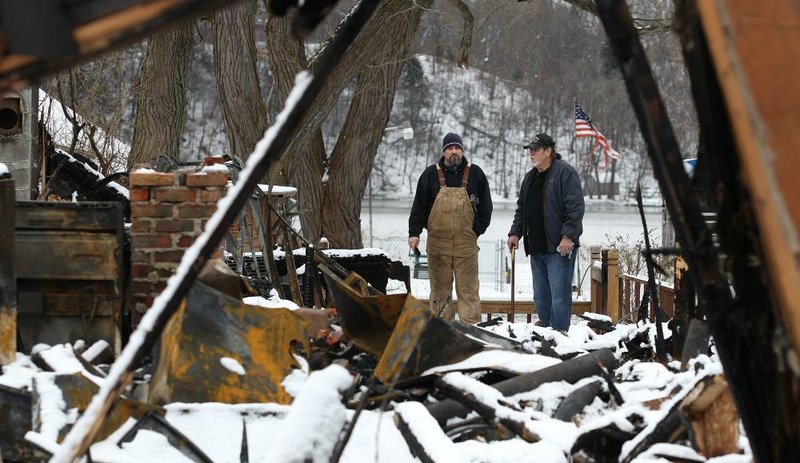 Ken Horn Jr. (left) and Ken Horn Sr., examine what remains of the elder Horn’s house in Webster, N.Y., on Wednesday. Horn’s house was burned Christmas Eve when neighbor William Spengler set ÿre to his own house before killing two ÿ reÿghters who responded. 