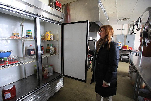 Georgia Mjartan, executive director of the Our House shelter in Little Rock, looks at what food remains Thursday after an extended power failure led to spoilage. 