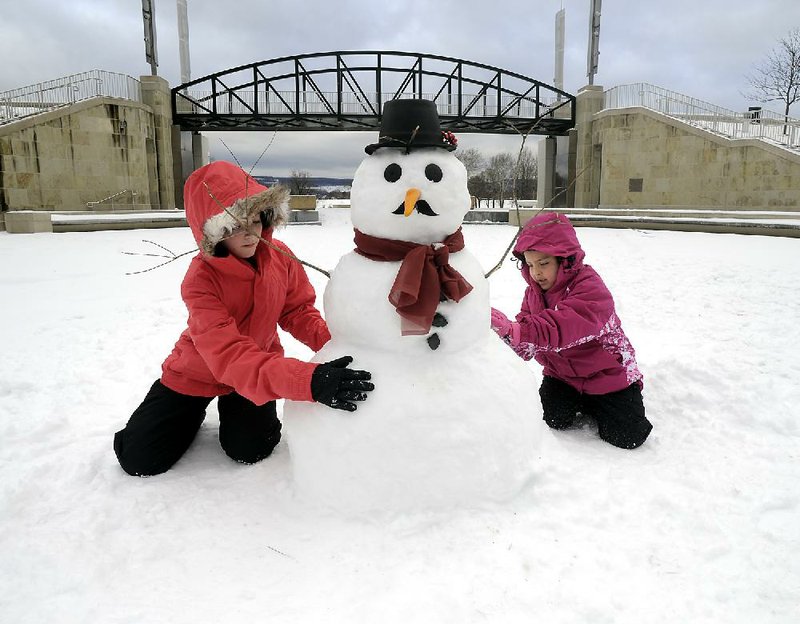 Desiree Smith, 13, and Madison Garza, 7, both of San Diego, build a snowman Thursday in Wilkes-Barre, Pa., where the girls and their families were visiting relatives. The two had never seen snow before and built their first snowman. 