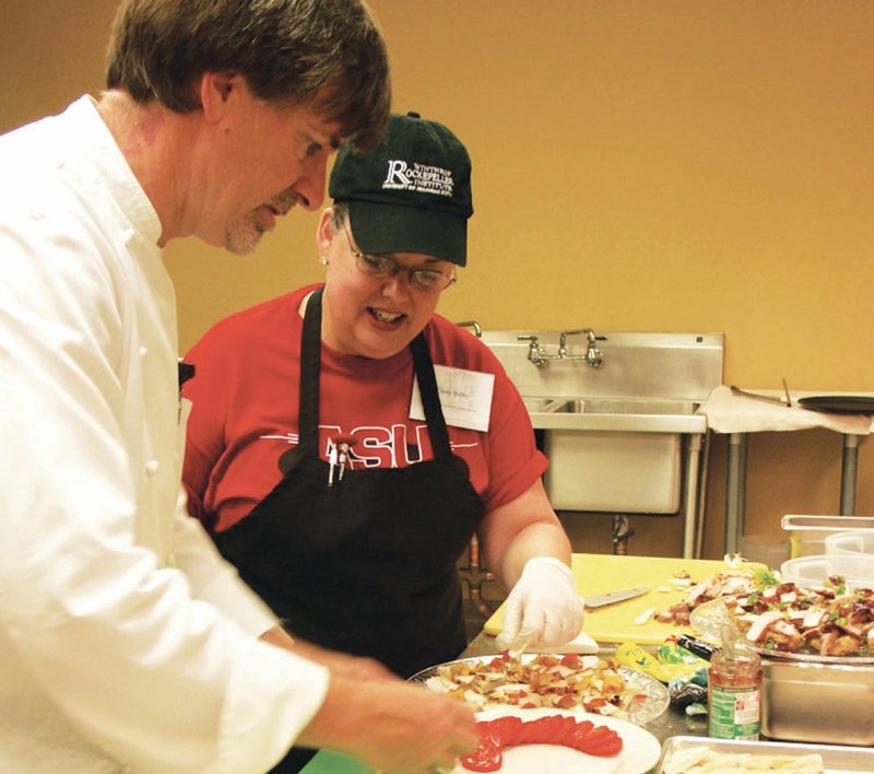 Cindy Bailey observes a plating technique demonstrated by University of Arkansas professor and chef Robert Harrington during a class at Arkansas State University-Heber Springs. The hospitality management program at ASU-Heber Springs will return this spring. 