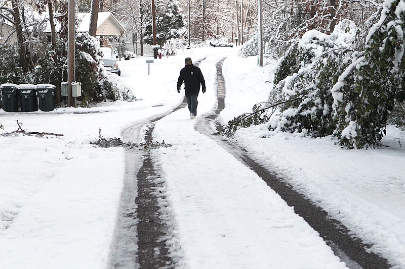 John Bomar of Hot Springs walks along snow-covered Ledgerwood Road on Wednesday, following the Christmas winter storm that dumped more than a foot of snow on parts of the Tri-Lakes Edition coverage area.