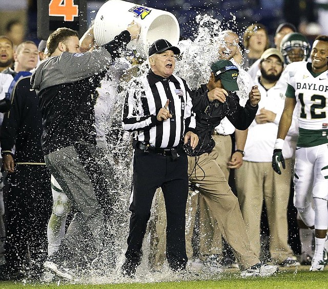 Head linesman R.G. Detillier (left) gets caught in the shower when Baylor Coach Art Briles is doused during a post game water bath after the Bears’ 49-26 victory over UCLA in the Holiday Bowl on Thursday in San Diego. 