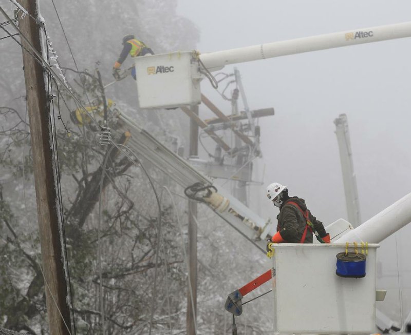 Fog blankets utility workers Friday as they repair broken power lines along Cantrell Road in Little Rock. Tree limbs weighed down from ice and snow Tuesday night snapped power lines across the state and initially left more than 200,000 electric customers without power.


