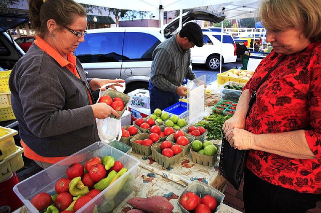 Gloria Castenholz (right) purchases tomatoes at the Union Street Farmers Market in downtown Gainesville, Fla., in November. Florida tomato growers are leading an effort to curtail rules that make it easy for Mexican farmers to export their crops to the United States. 