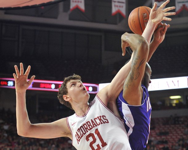 University of Arkansas forward Hunter Mickelson and Northwestern State forward DeQuan Hicks fight for a rebound the first half of Saturday night's game. Mickelson and BJ Young both finished with a 13 rebounds, a career high for each player.