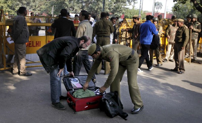 A policeman checks luggage Saturday at a police barricade set up where protesters gathered Saturday to mourn a gang-rape victim in New Delhi. 